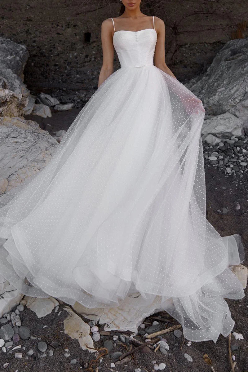 Model wearing a simple A-line spaghetti strap wedding dress, front view.