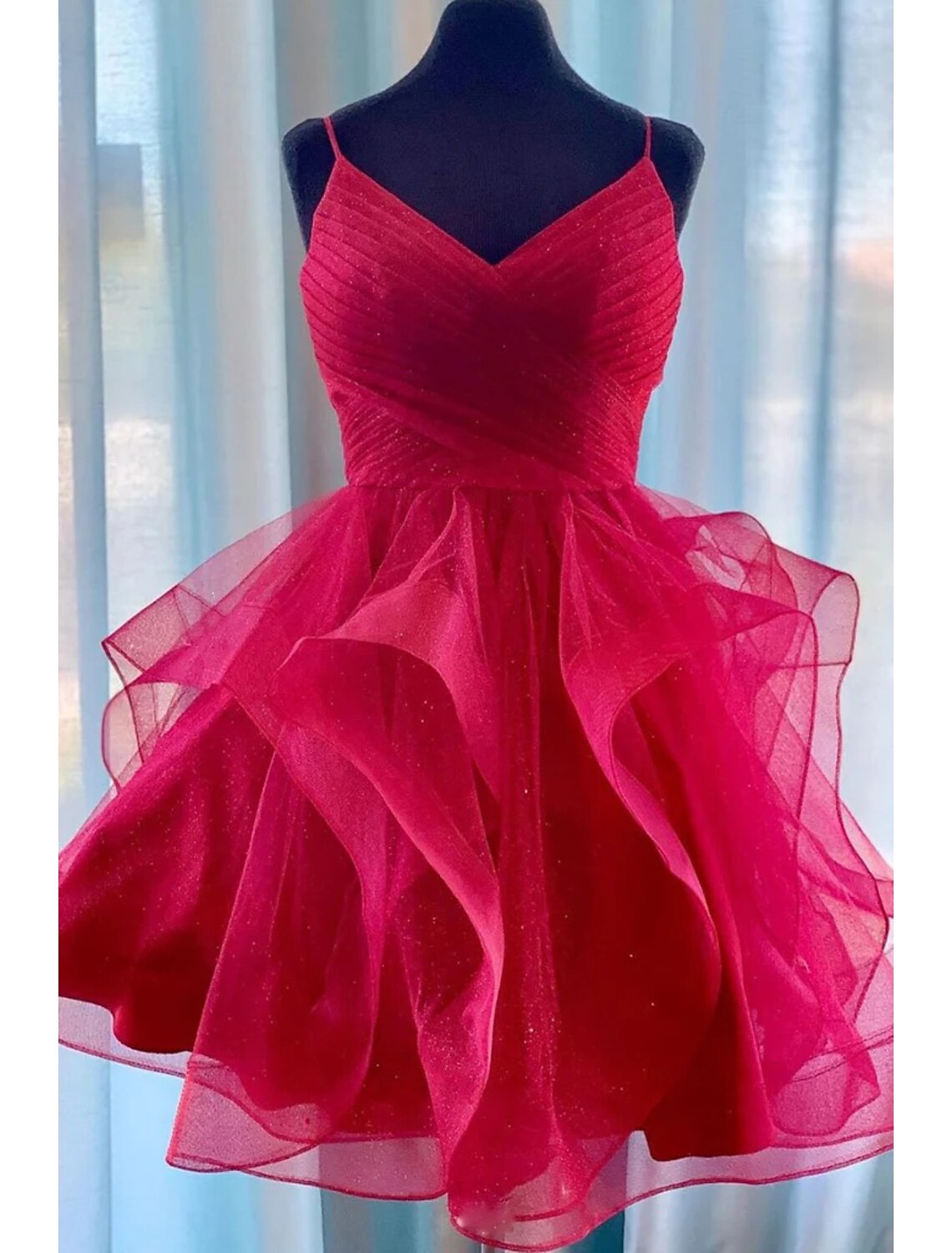 Model wearing a sparkling A-line ball gown with spaghetti straps and knee-length glitter tulle skirt.