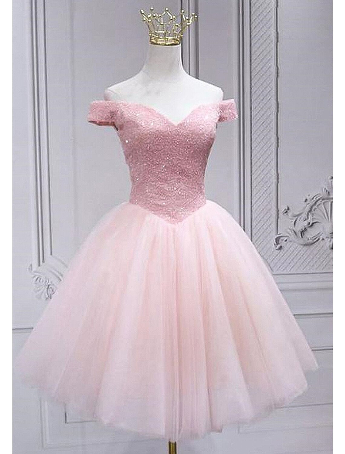 Model wearing a sparkling A-line off-shoulder sequin tulle knee-length homecoming dress, front view.