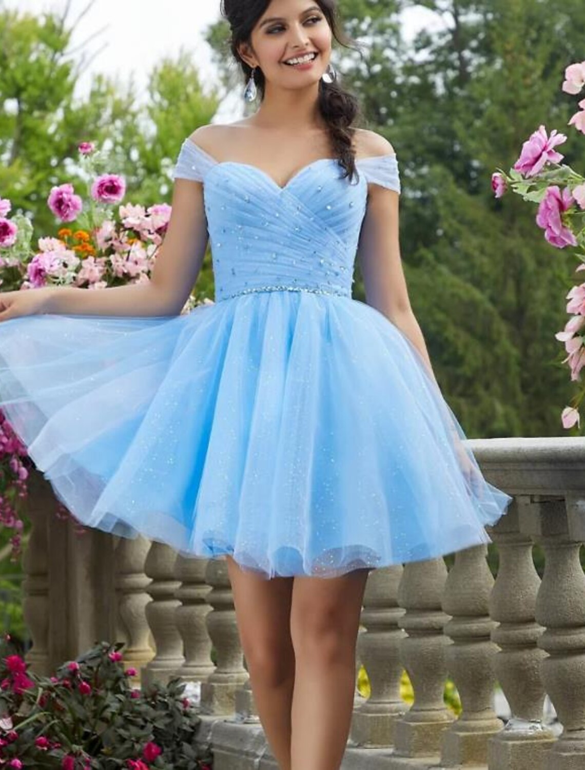 Woman wearing a sparkling A-line mini cocktail dress with sweetheart neckline and short sleeves.