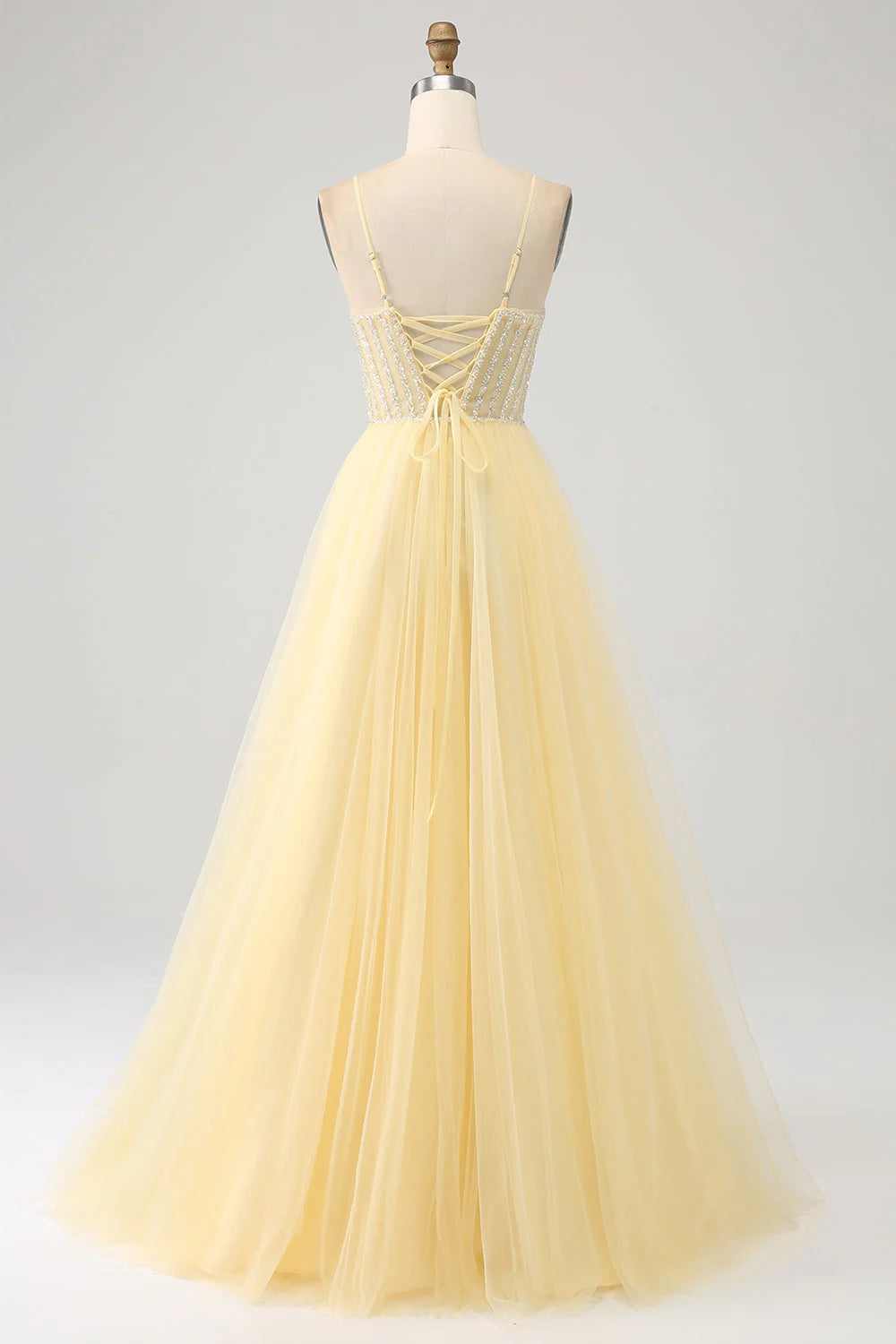 Back view of a light yellow beaded tulle prom dress.