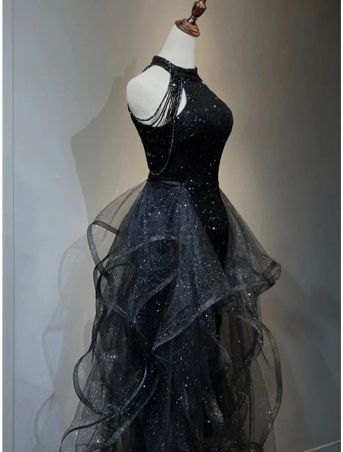 Side view of a woman wearing a shimmering sequined maxi gown.