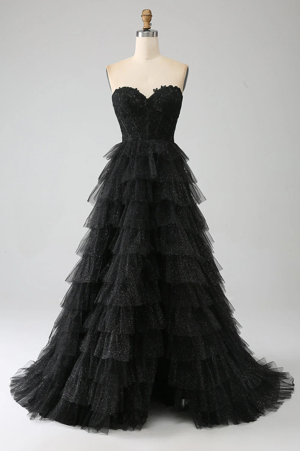 Model wearing a black glitter corset prom dress with a high slit.