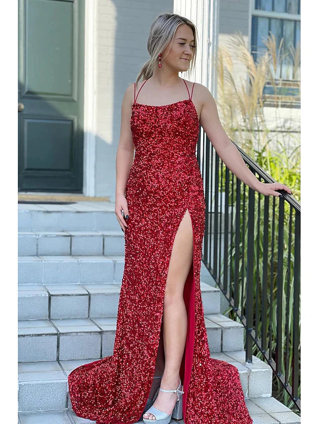 Model wearing a sparkling sequined mermaid prom dress with spaghetti straps and a slit.