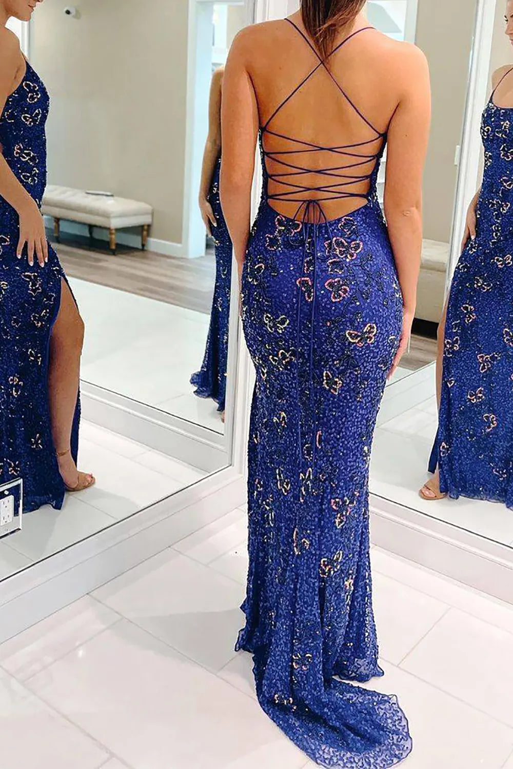 Back view of a woman in an embroidered mermaid prom dress with spaghetti straps.