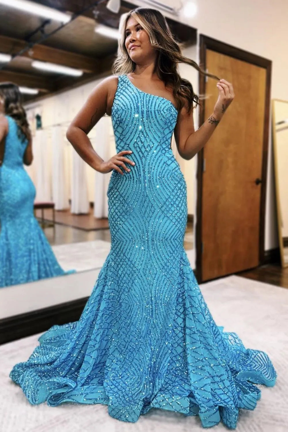 Woman wearing a sparkling one-shoulder mermaid prom dress.