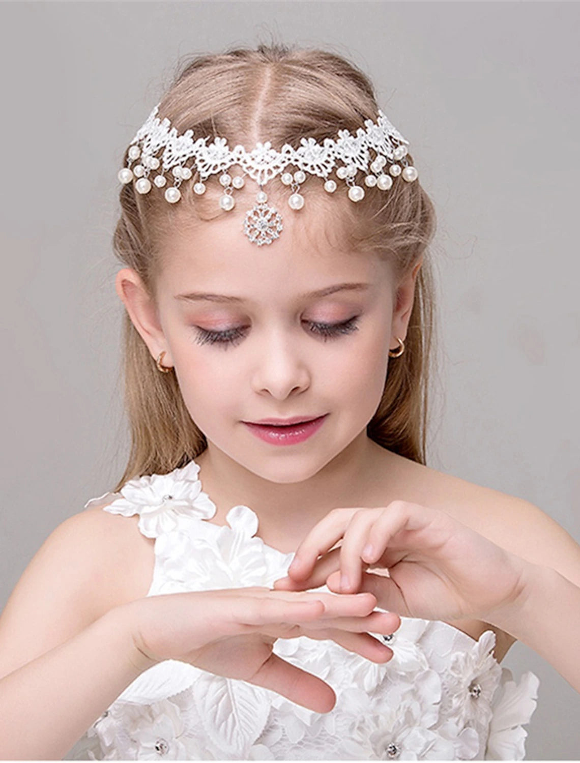 Close-up of a sparkling princess tiara head chain with crystal and pearl details.