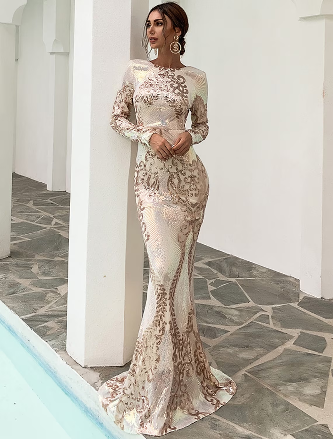 Woman wearing a sparkling sequin mermaid evening gown with long sleeves and a jewel neck.