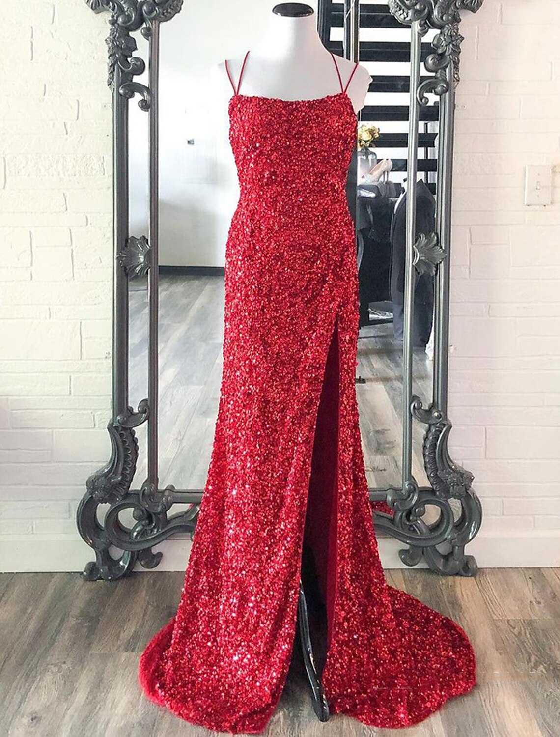 Model wearing a sparkling sequin mermaid prom dress with spaghetti straps and a high slit.