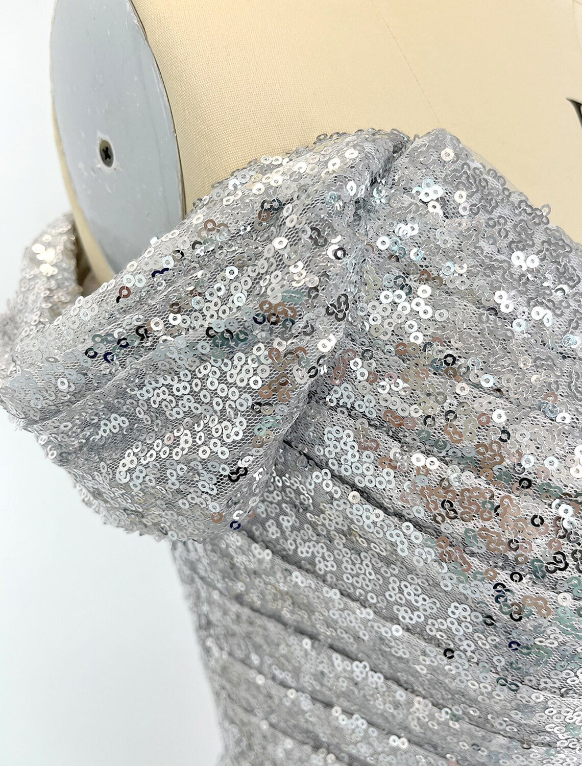 Woman wearing a sparkling sequined mermaid evening gown, back view showing the silhouette.