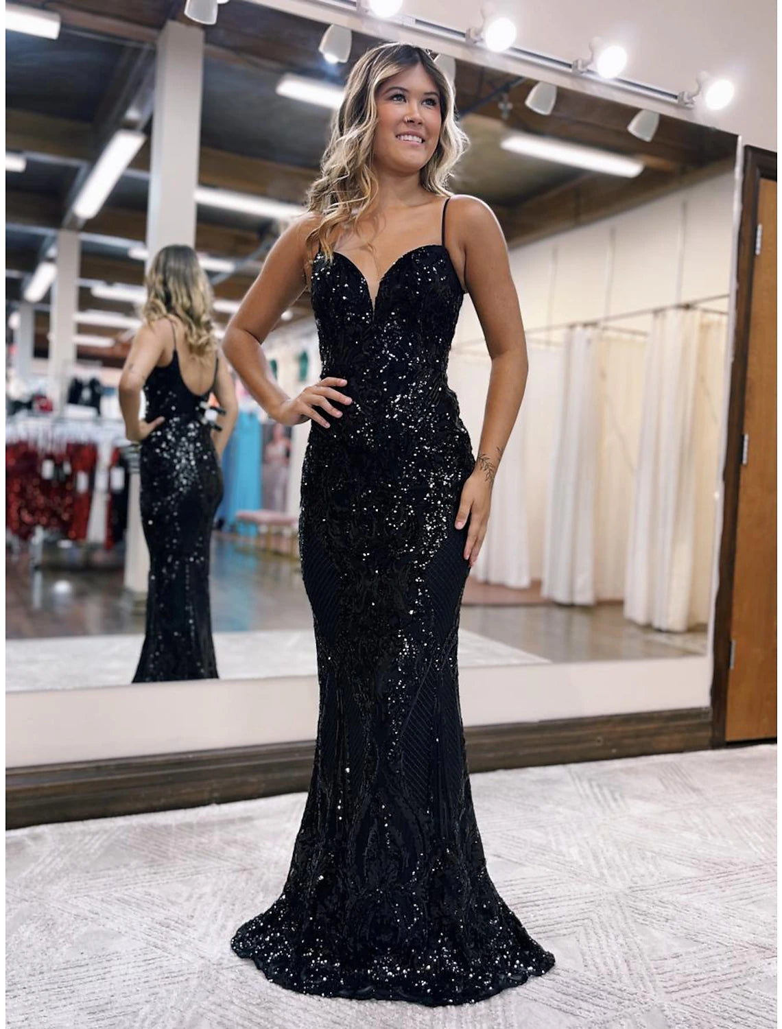Model wearing a sparkling sequined mermaid prom dress with a V-neck and sweep train.