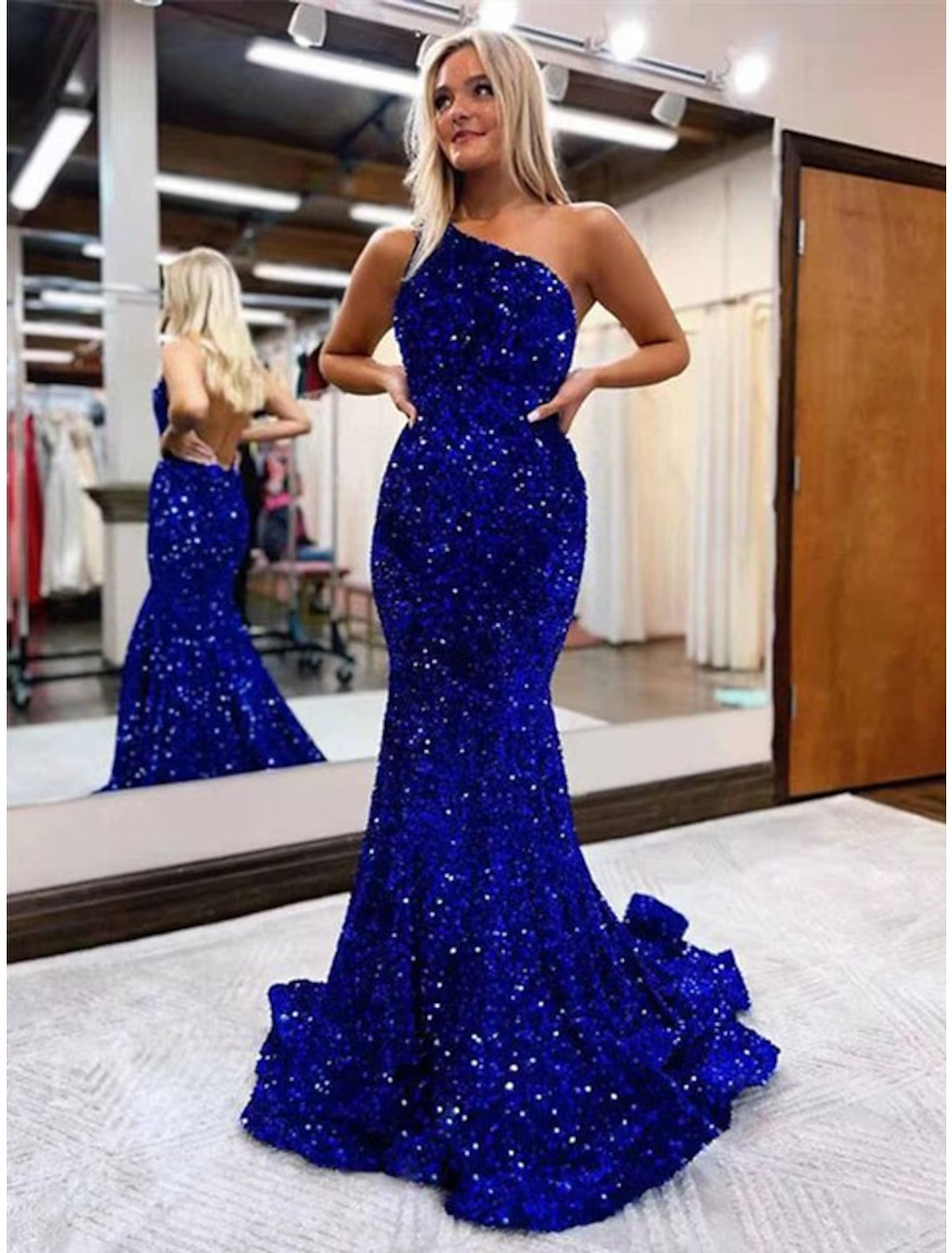 A woman wearing a sparkling sequined one-shoulder mermaid trumpet prom dress.