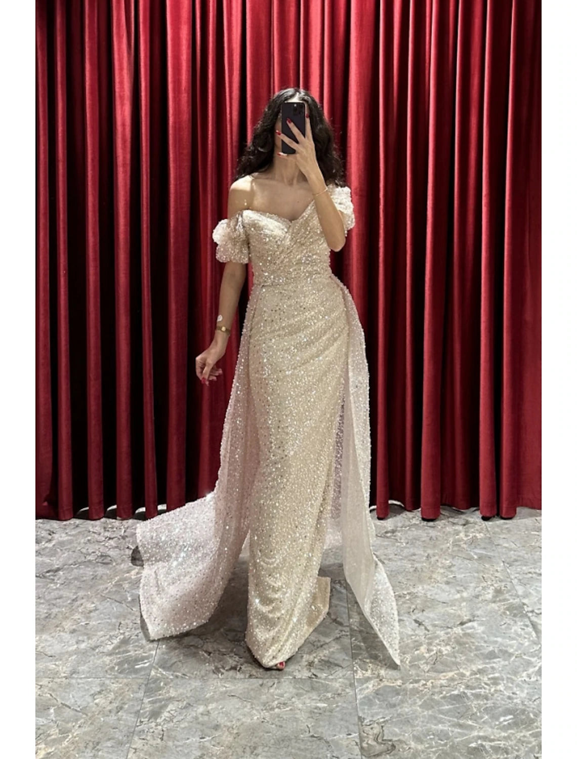 Woman wearing a sparkling sequined sheath evening gown with V-neck and short sleeves.