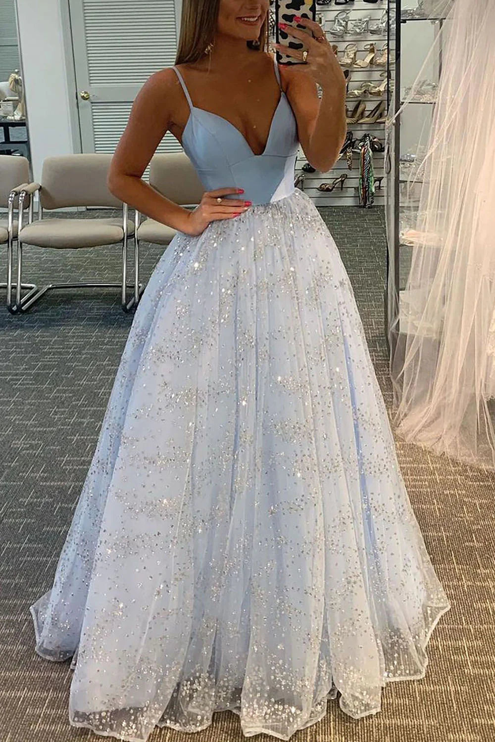 Model wearing a sparkling long tulle prom dress with spaghetti straps, posing elegantly.