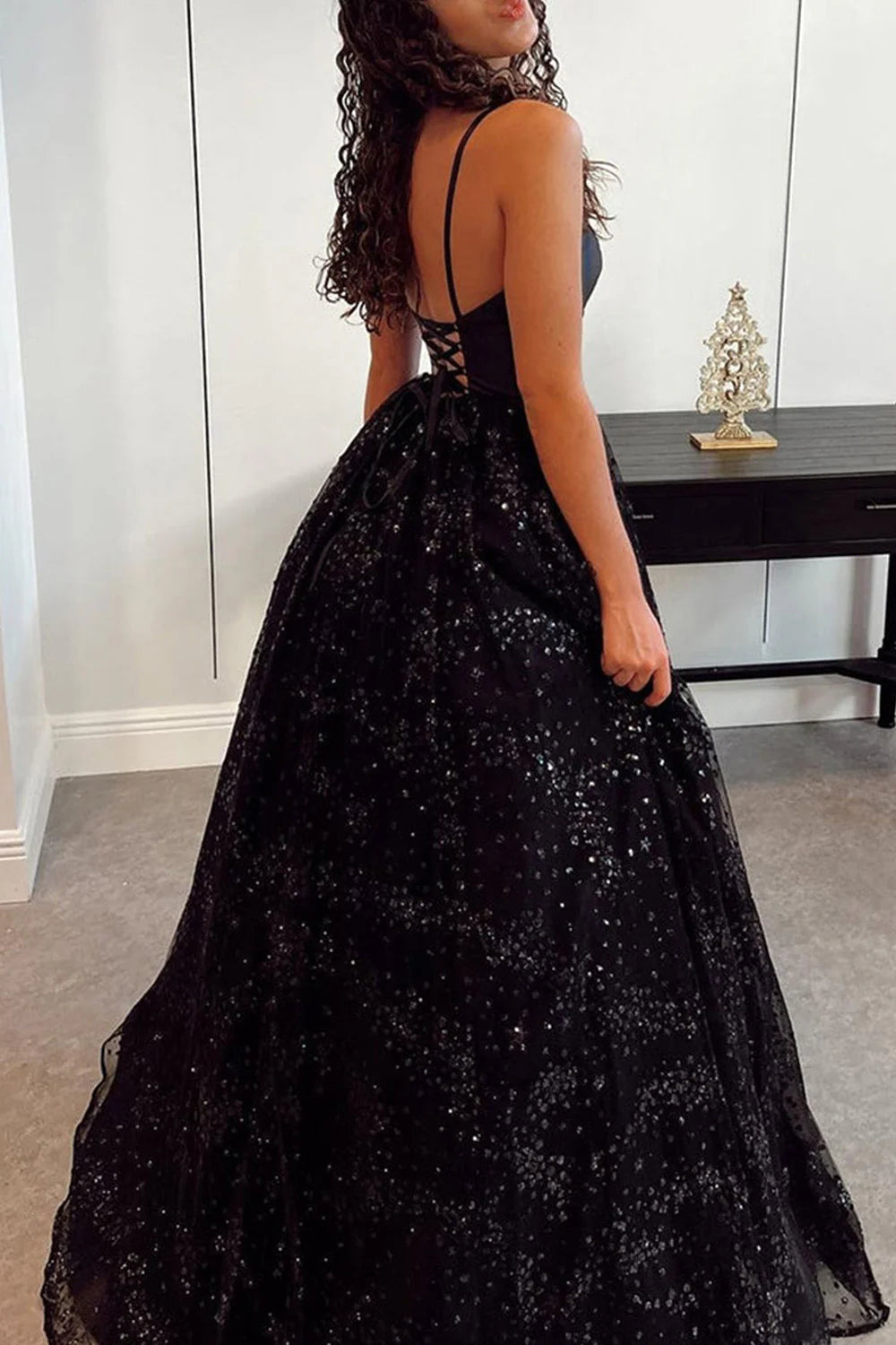 Side view of a model wearing a long sparkling tulle formal dress, highlighting the silhouette.