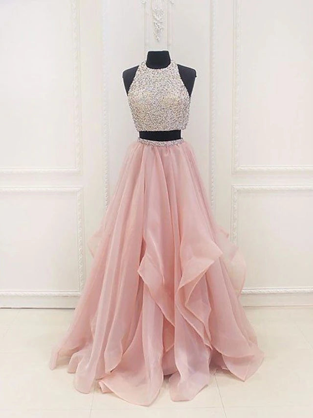 Model wearing a sparkling two-piece halter ball gown prom dress with sequin details and a floor-length organza skirt.