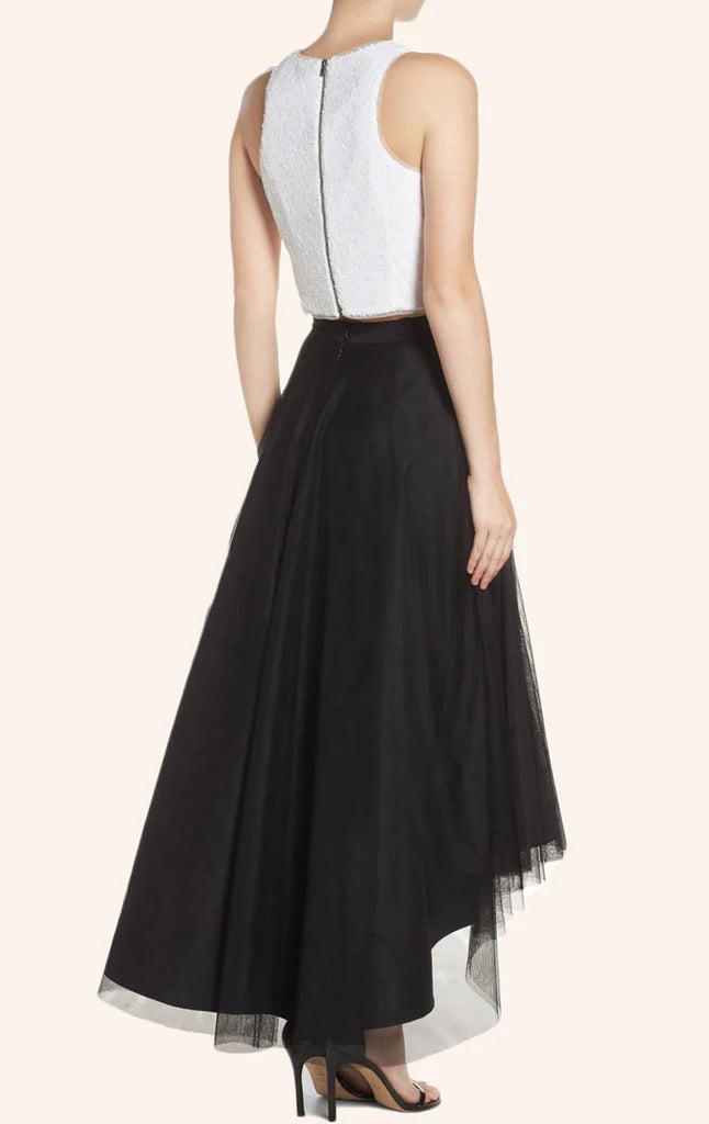 Side view of a woman in a two-piece sequin top and flowing tulle high-low skirt.