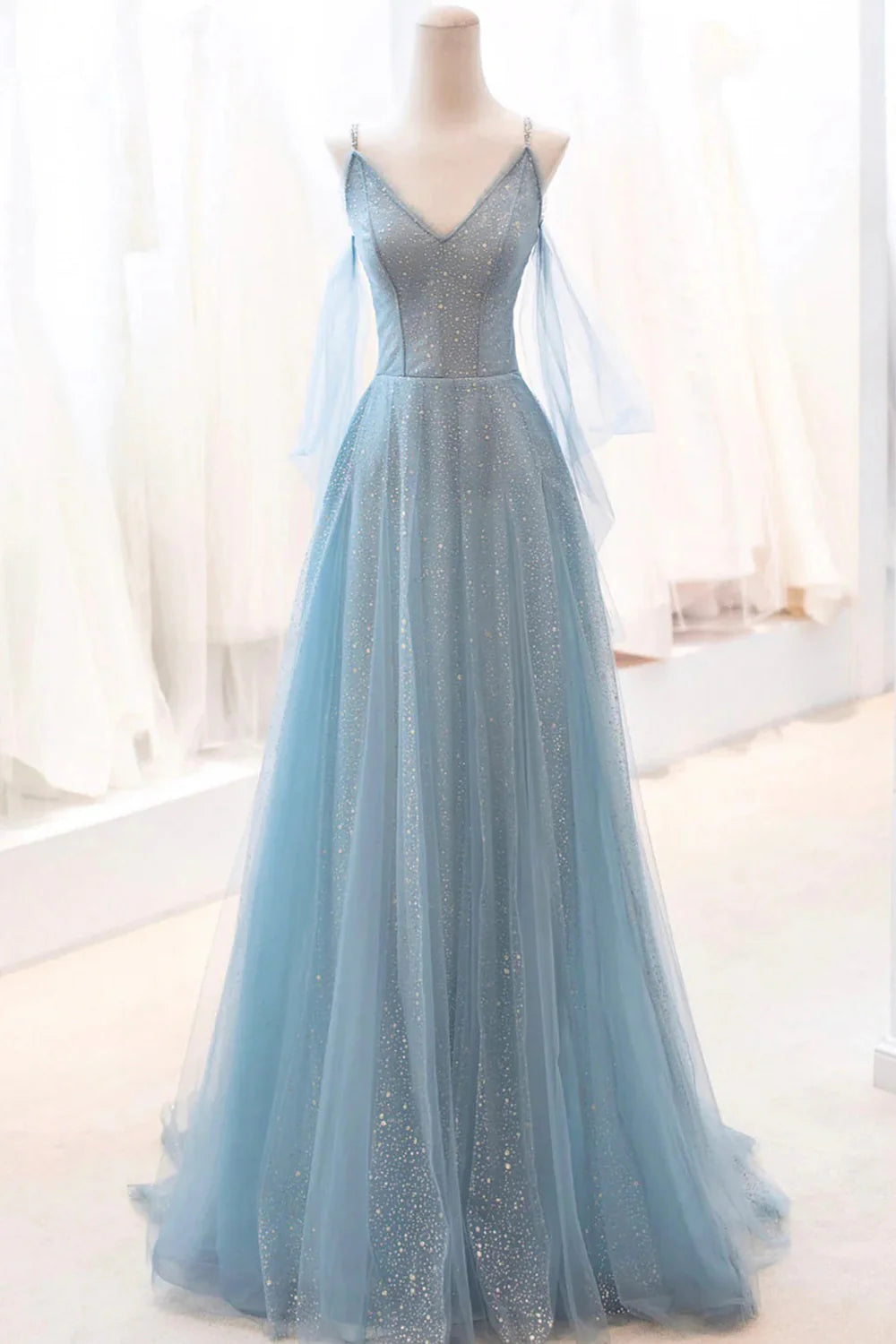 Model wearing a sparkly A-line long prom dress with spaghetti straps and tulle skirt.