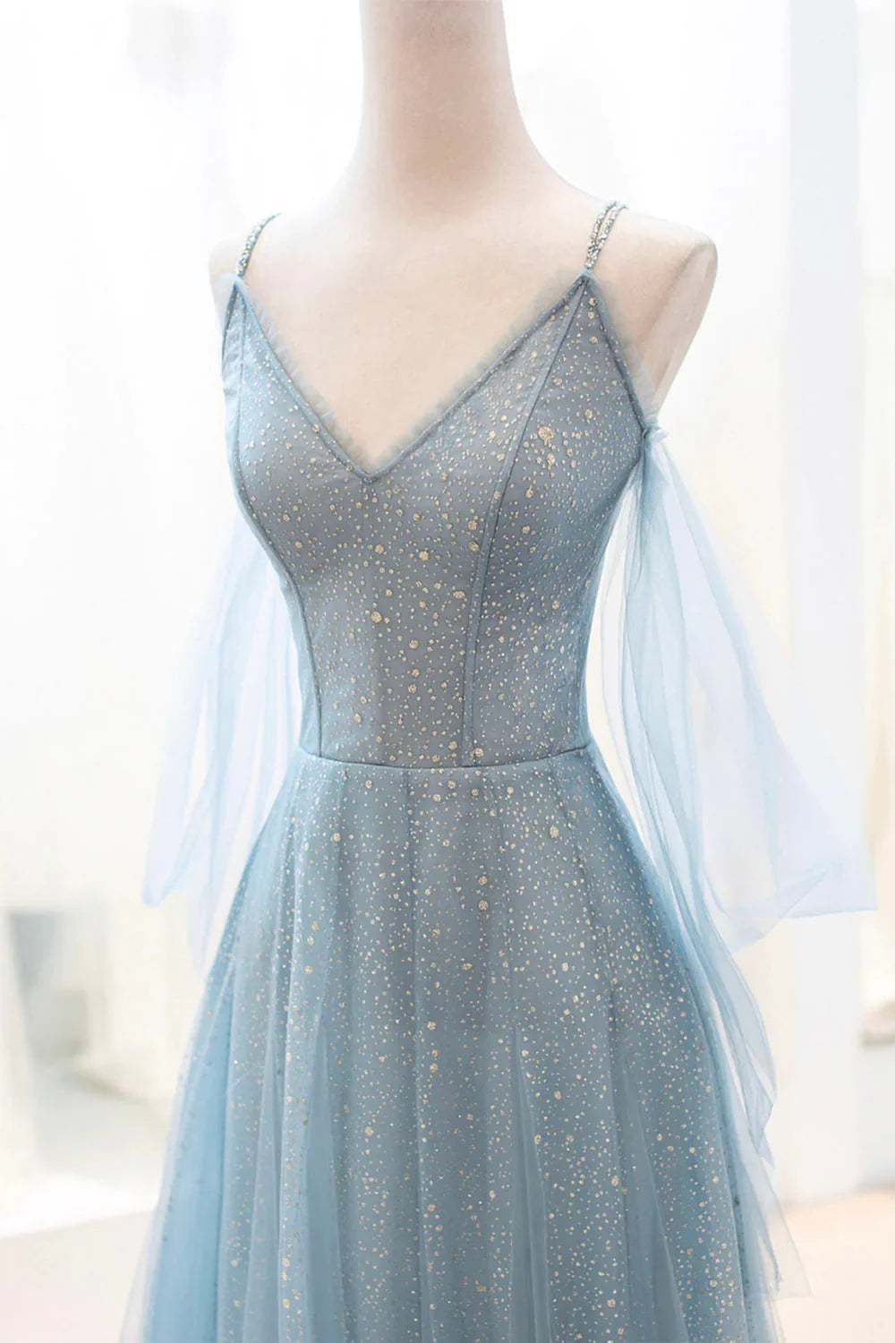 Close-up of the sparkly tulle fabric and spaghetti straps on a long prom dress.
