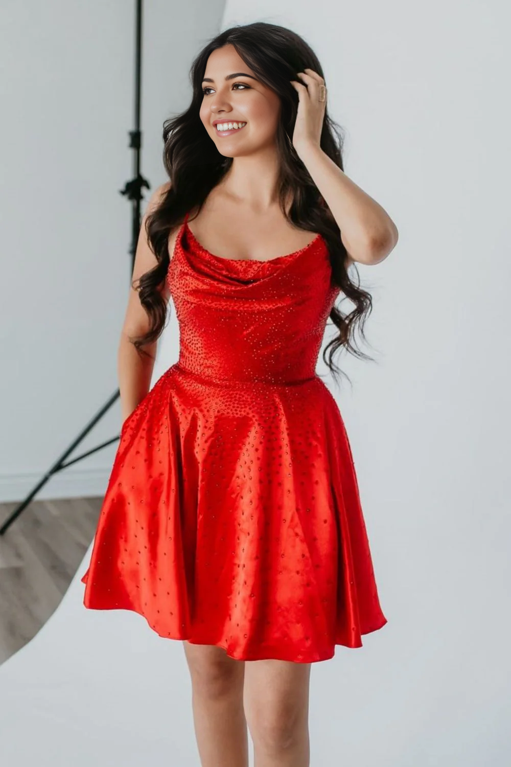 Model wearing a sparkly red A-line homecoming dress with spaghetti straps and beaded details.