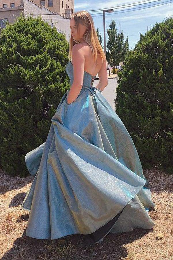 Model wearing a sparkly A-line strapless sweetheart prom dress with pockets.