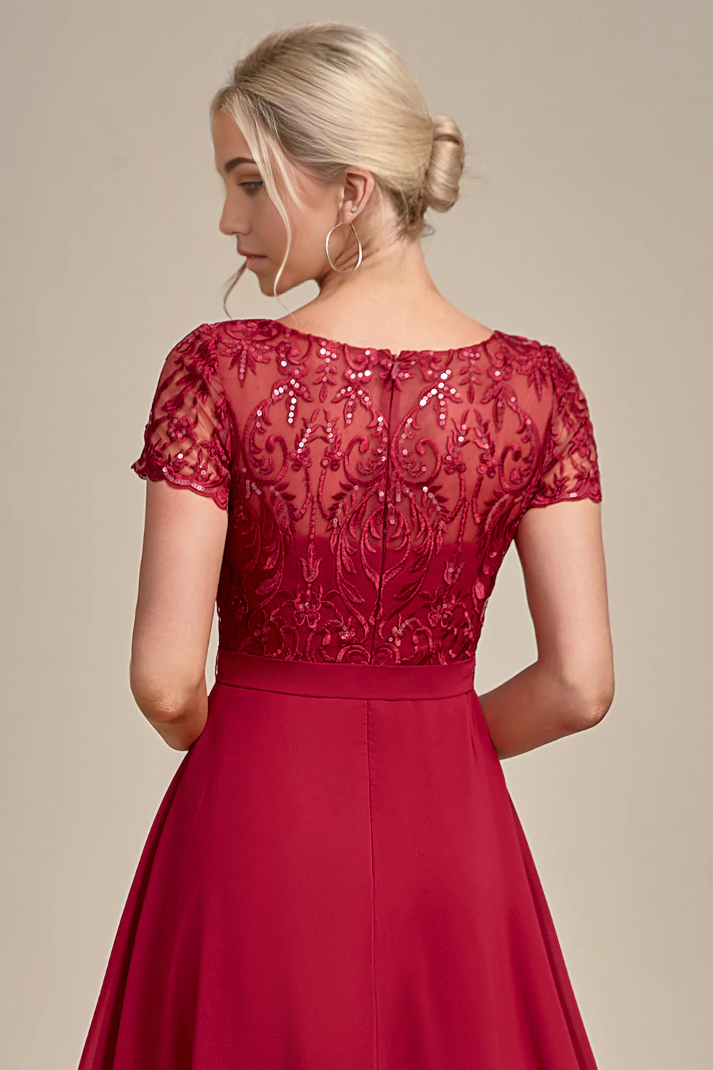 Close-up of the asymmetrical sequin and applique details on the burgundy dress.