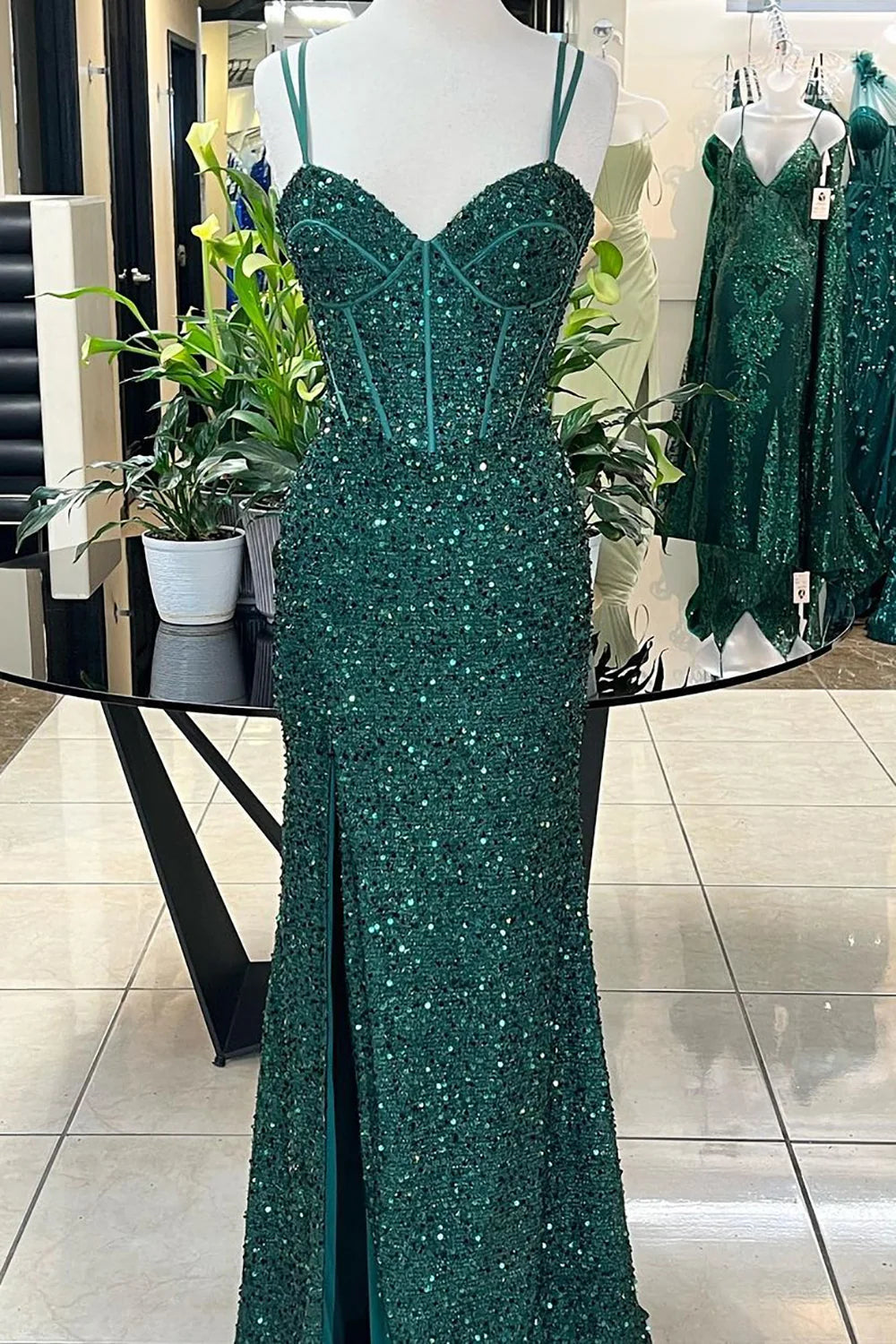 Woman wearing a sparkly mermaid prom dress with a corset bodice and high slit.