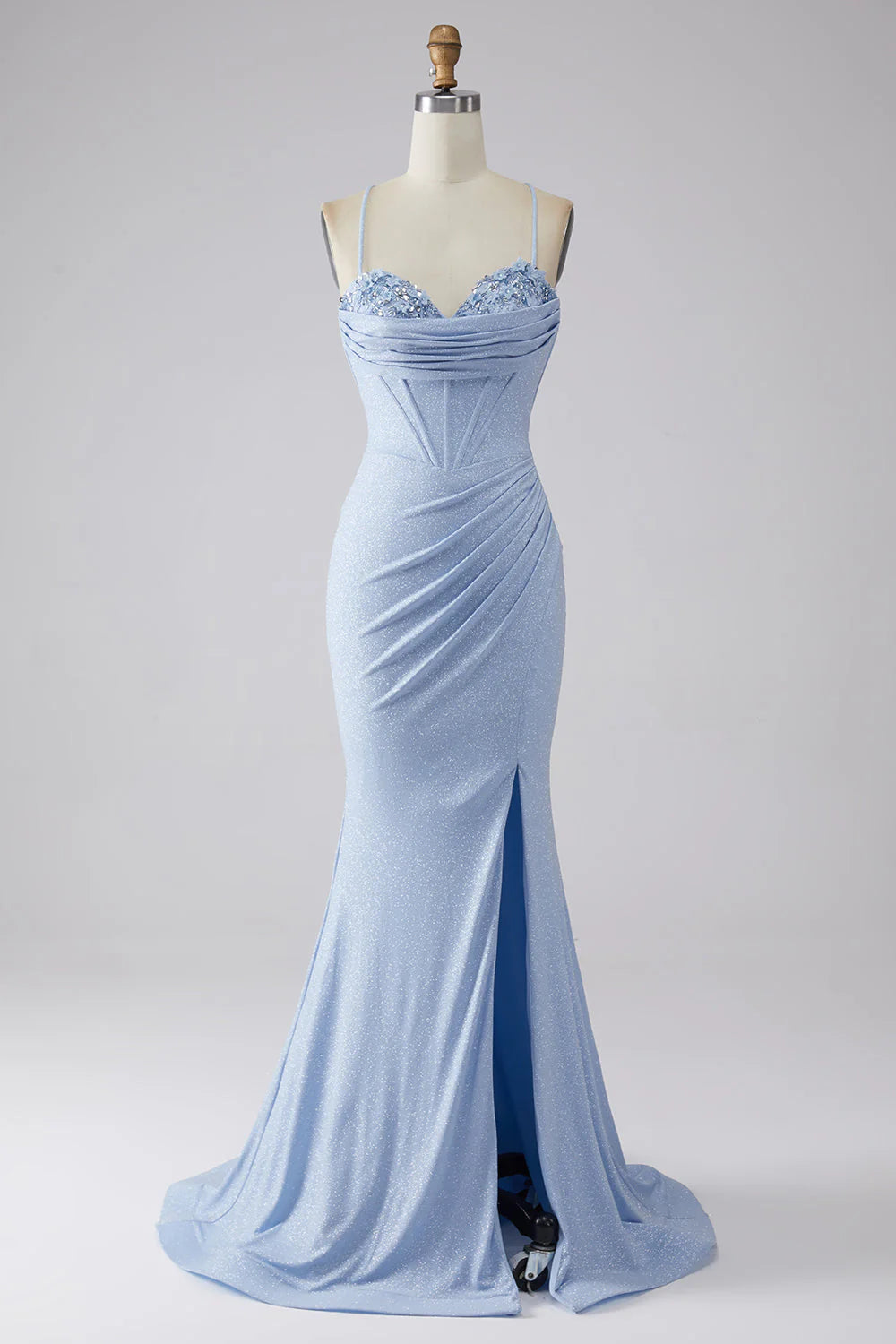 Model wearing a sparkly mermaid prom dress with a high slit, posing elegantly.