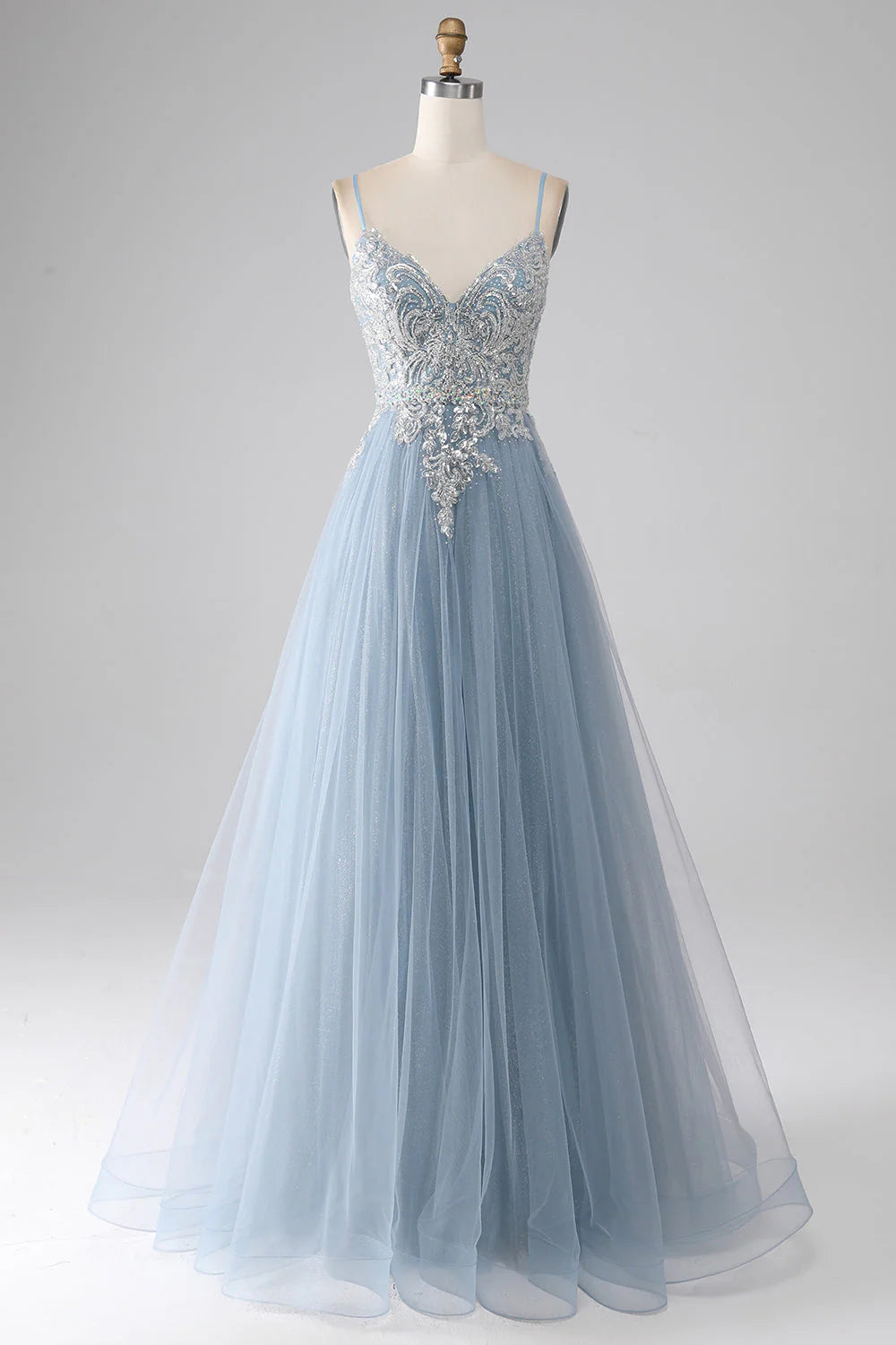 Model wearing a sparkly grey-blue mermaid prom dress with spaghetti straps.