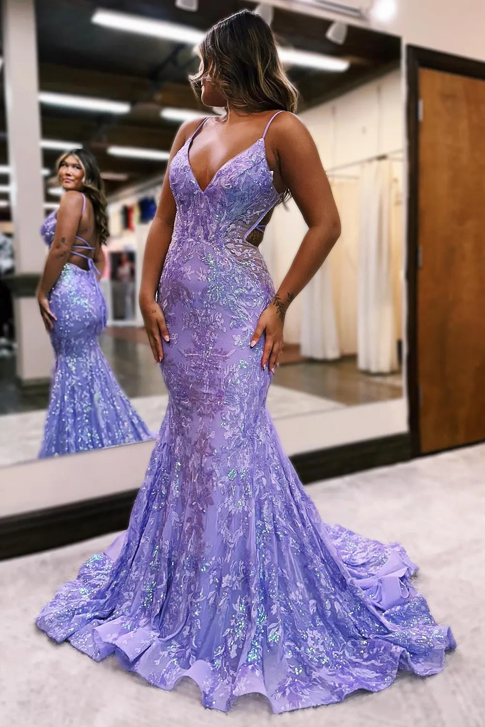 Full view of a woman wearing a sparkly mermaid sequin prom dress with spaghetti straps and a backless design.