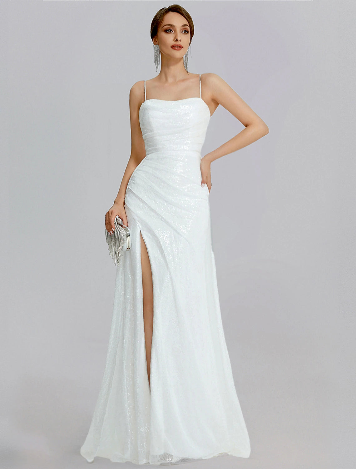 Woman wearing a sparkly mermaid trumpet dress with a cowl neck and ruched slit.