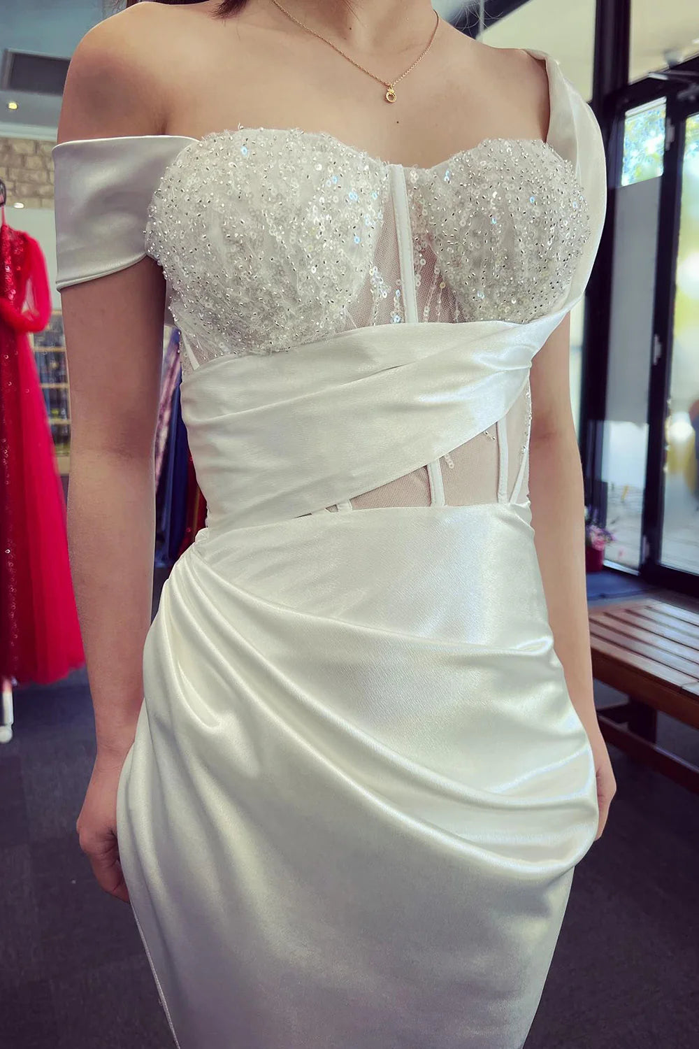 Model posing in a sparkly off-shoulder corset prom dress, side view.