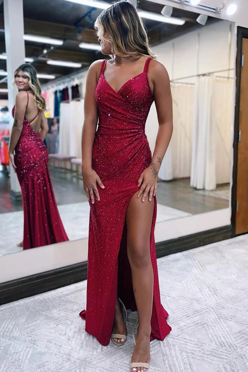 Model wearing a sparkly one-shoulder sheath prom dress with a high slit, posing elegantly.