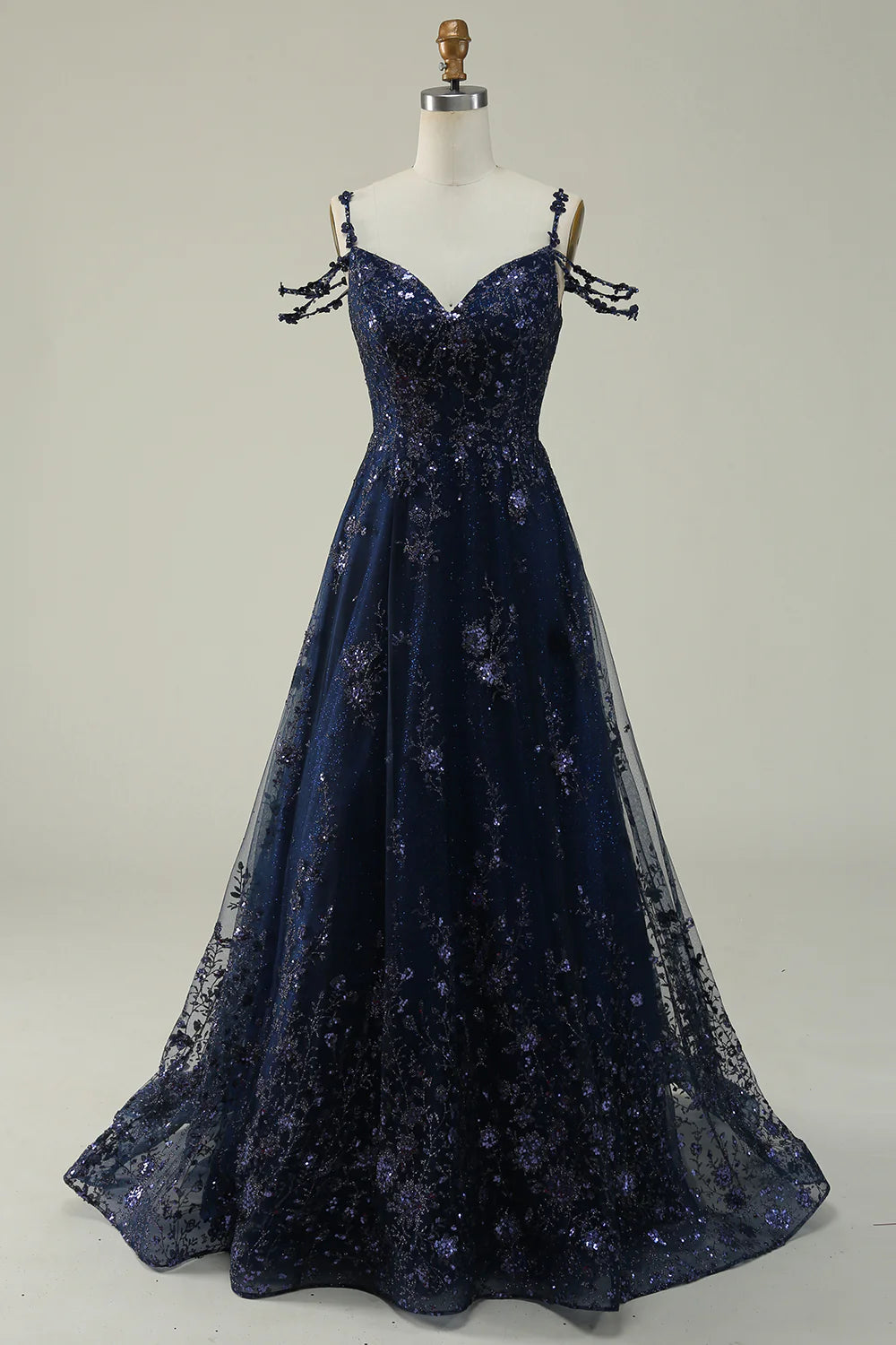 Front view of a woman wearing a navy sparkly sequin ball gown dress with spaghetti straps.