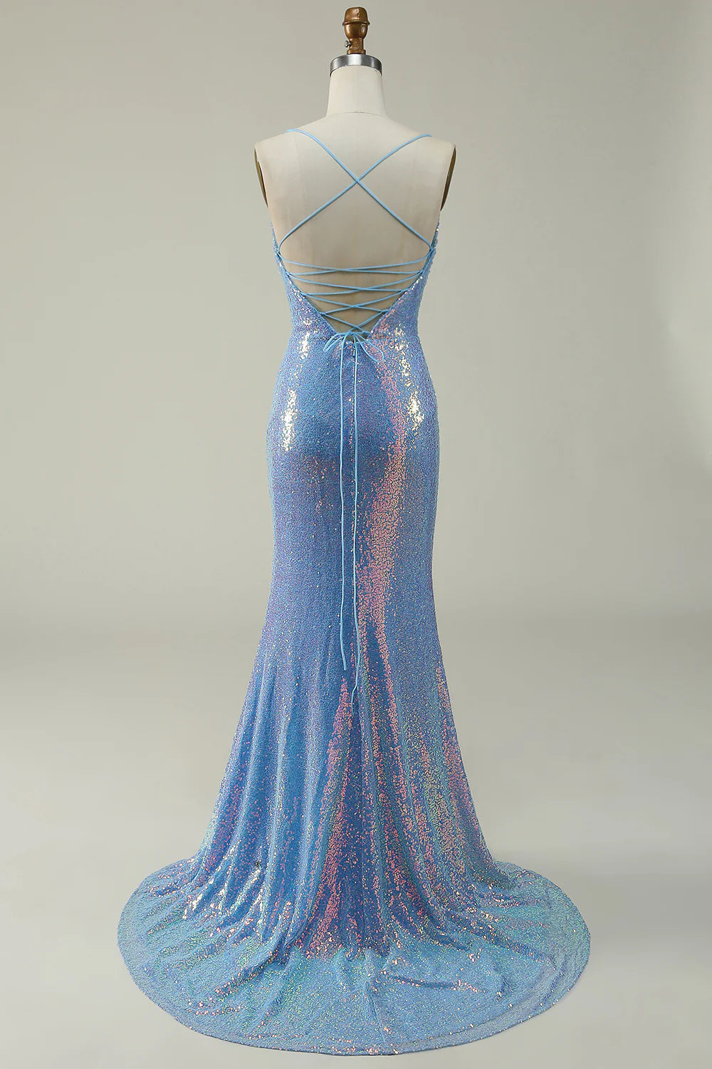 Side view of a woman wearing a blue sequin mermaid prom dress with a slit.