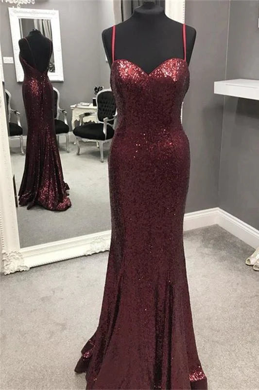 Woman wearing a sparkly sequined mermaid prom dress with spaghetti straps and a backless design.