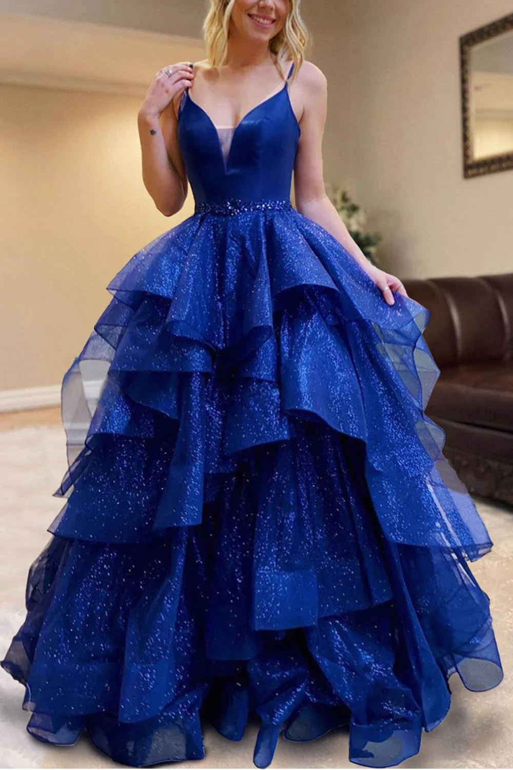 Model wearing a sparkly tiered tulle prom dress with spaghetti straps, showcasing the full length and elegant design.