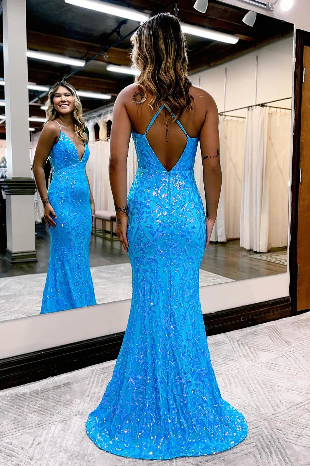 Back view of a woman in a sparkly V-neck spaghetti strap long mesh prom dress, showcasing the flowing skirt.
