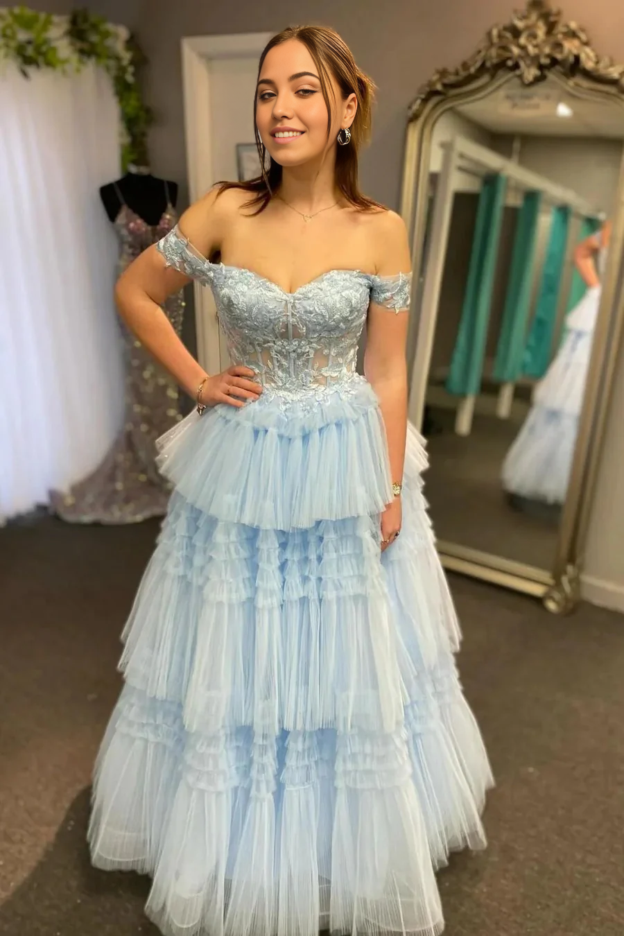 Light blue A-line off-shoulder prom dress with corset, ruffles, and appliques.