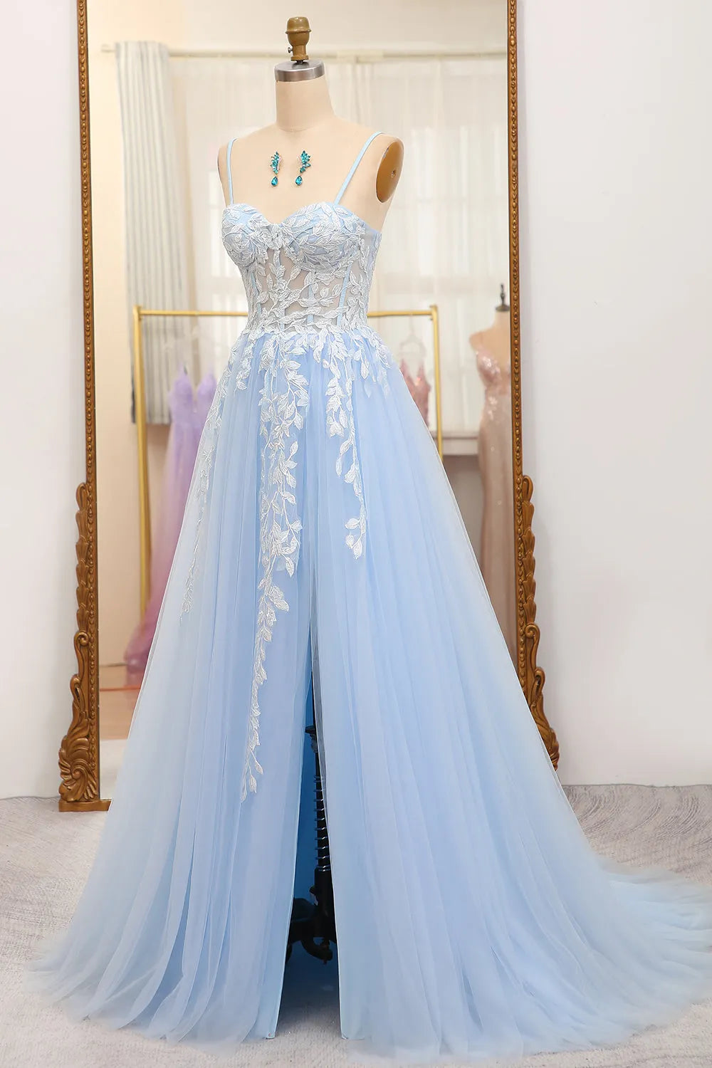 Model posing in a flowing sky blue A-line prom dress with appliques.
