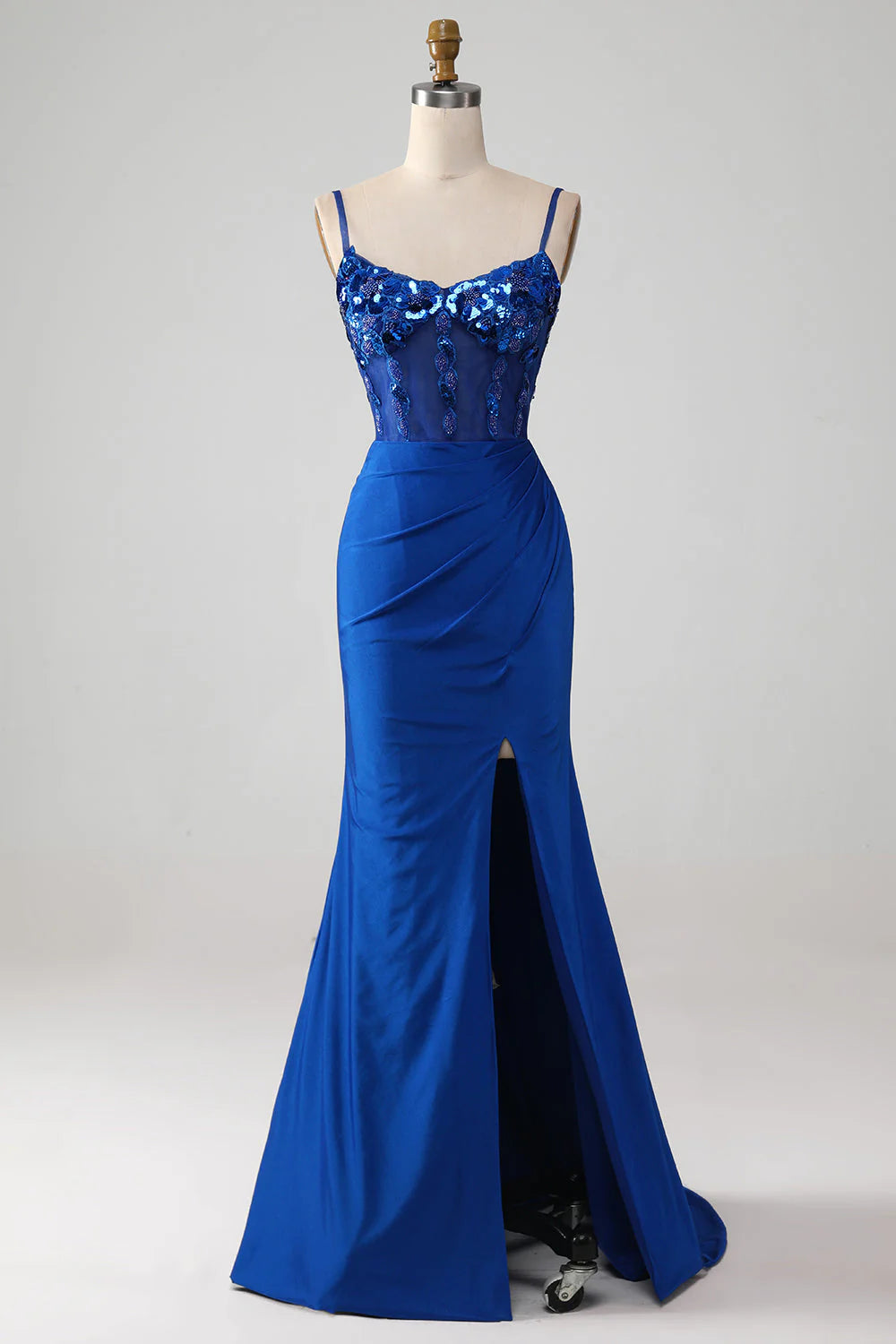 Model wearing a royal blue beaded corset prom dress with a high slit, posing elegantly.