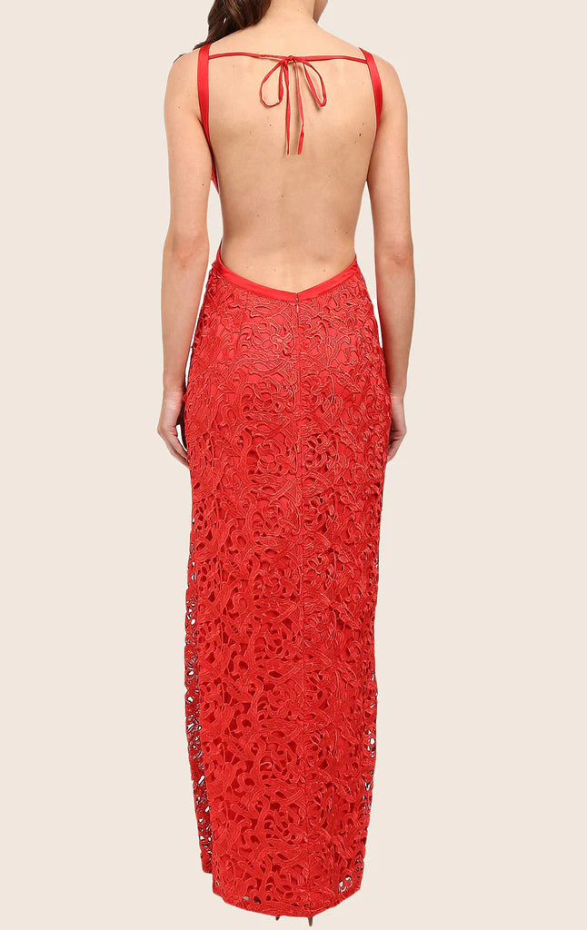 Back view of a woman in a flowing halter neck lace formal gown.