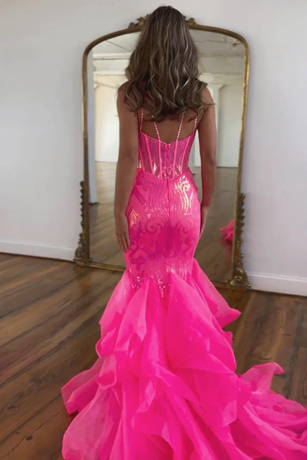 Close-up of the shimmering sequin fabric and delicate spaghetti straps on the hot pink dress.