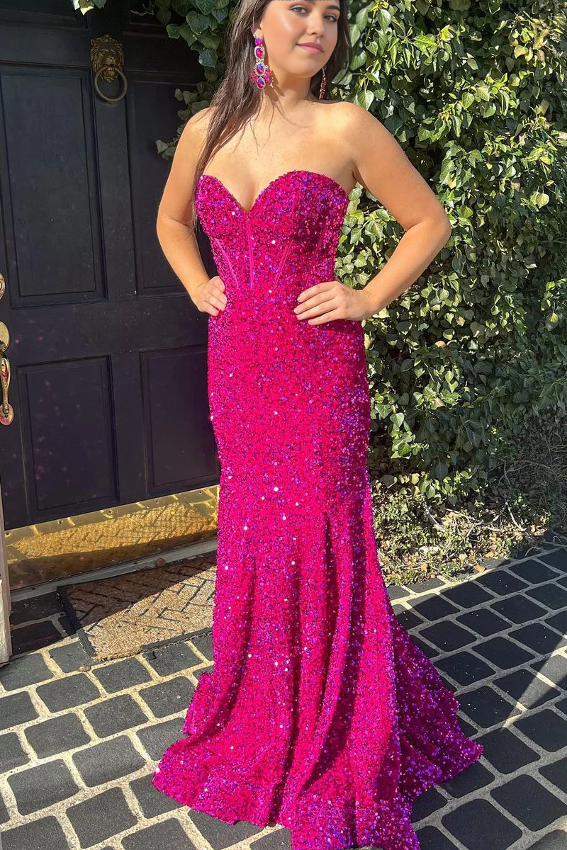 Woman wearing a long dragon fruit color sequin mermaid prom dress with a sweetheart neckline.