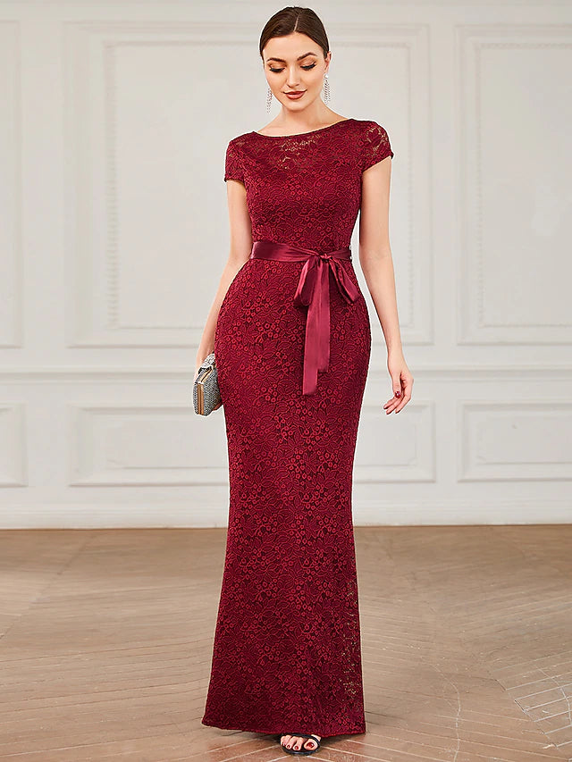 Woman wearing an elegant mermaid trumpet evening gown with short sleeves and a jewel neck.
