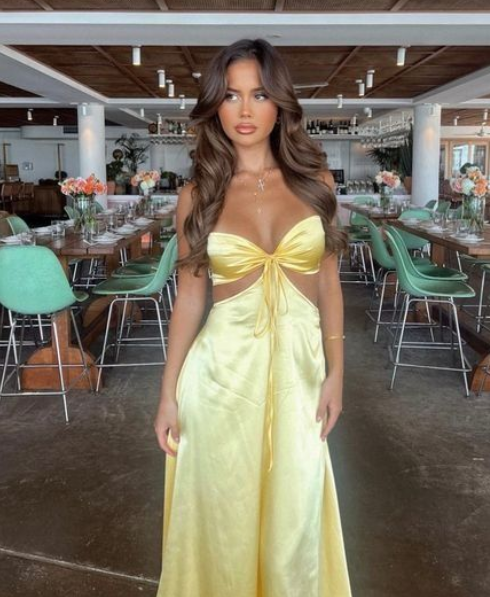 Woman wearing a navy mermaid prom dress with spaghetti straps and backless design.