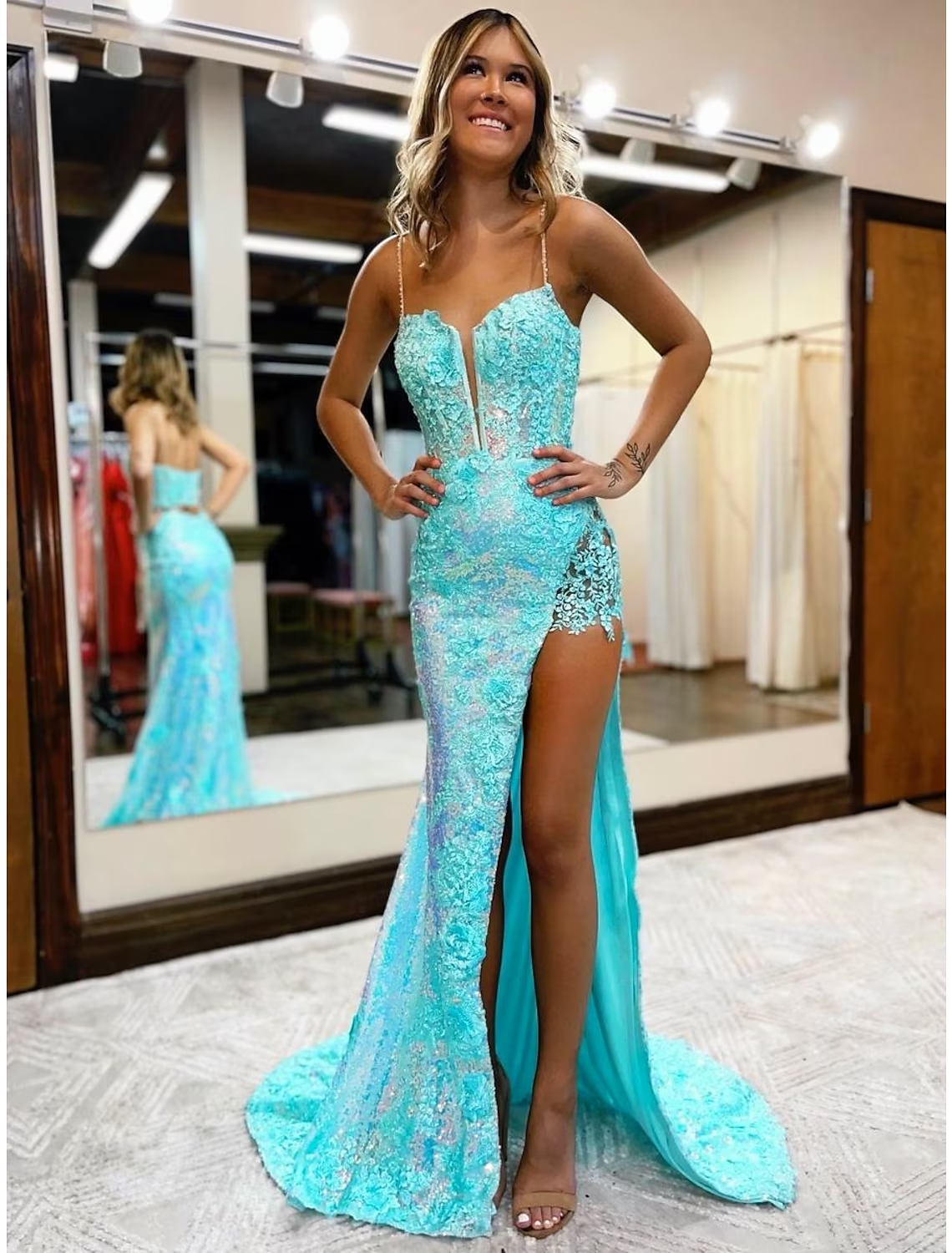 Model wearing a sequined mermaid V-neck prom dress with a high slit and court train.