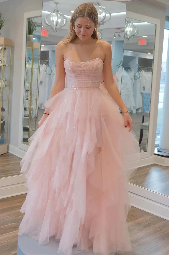 Full view of a woman wearing a strapless A-line sequin beaded tulle prom dress.