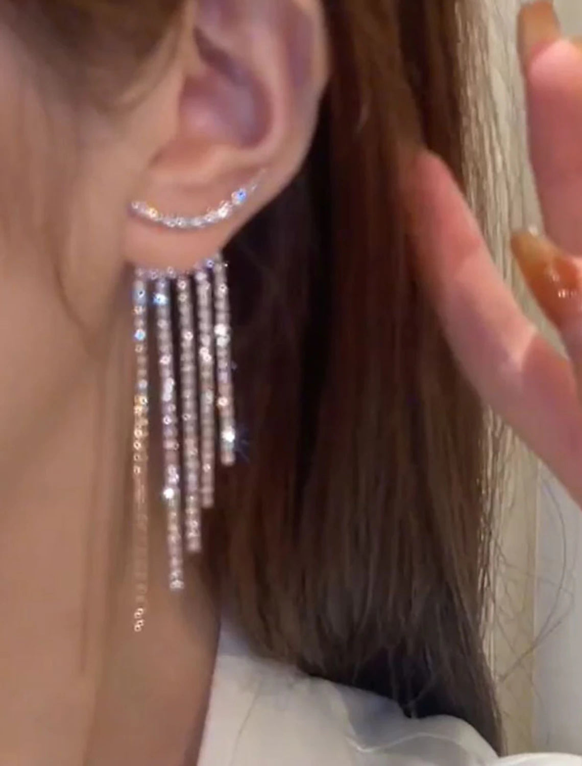 Close-up of a silver tassel fringe drop earring showing intricate details.