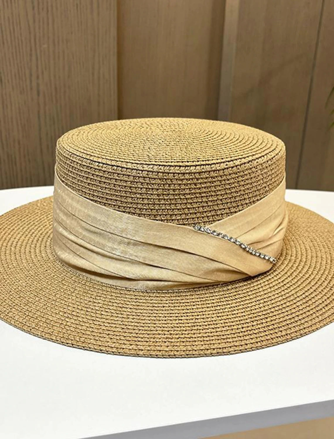 Elegant straw fascinator hat with bows and crystals on a model.